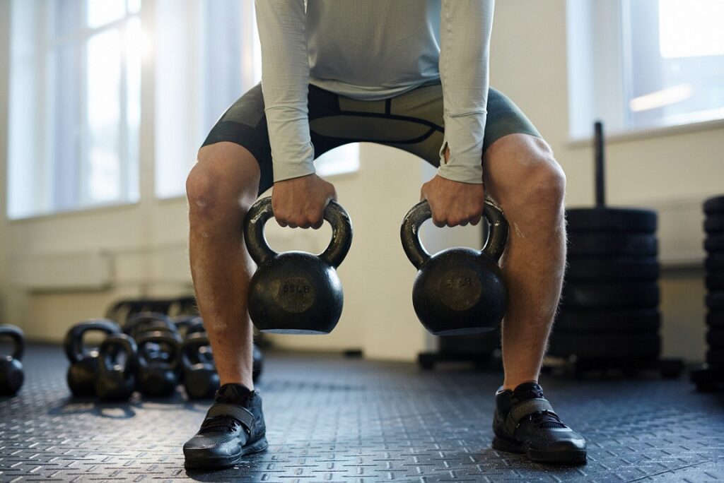 Man with weightlifting shoes holding kettlebells