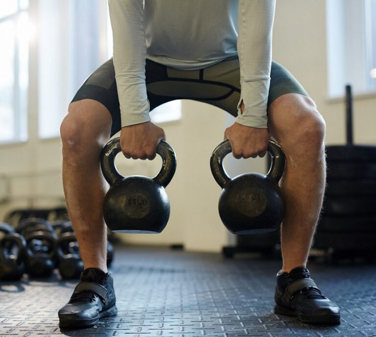 Man lifting kettlebells leaned forward
